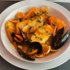 Caldereta de pescado con gambas, mejillones y almejas, todo ello espolvoreado con perejil fresco.