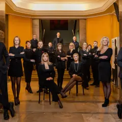 Grupa profesjonalistów w eleganckich strojach pozuje w holu.