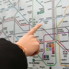 Palec wskazujący na mapę metra w Barcelonie, szukając trasy do Barcelona El Prat.
