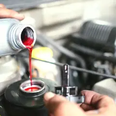 Maintenir la voiture en bon état : le liquide de frein rouge vif coule d'une bouteille dans le réservoir.