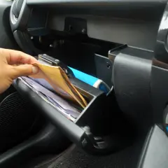 Ręka wyciąga dokumenty z schowka. Kierowca samochodu osobowego musi mieć przy sobie dowód rejestracyjny i polisę OC.