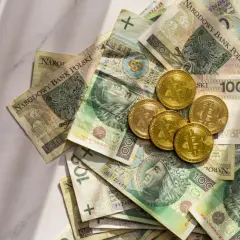 Złote monety Bitcoin leżą na stosie polskich banknotów 100 zł. Gdzie rozmienić pieniądze?