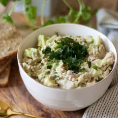 Pyszna pasta z awokado i tuńczyka, udekorowana natką pietruszki, podana z chlebem.