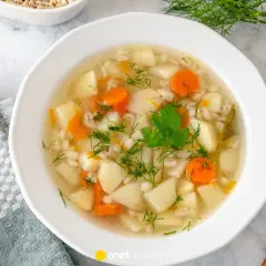 Aromaticzna, tradycyjna zupa jarzynowa z ziemniakami, marchewką i kaszą jęczmienną, udekorowana koperkiem.