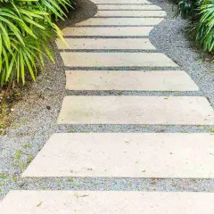 Un sentiero sinuoso con lastre di pietra per pavimentare giardino, circondato da ghiaia e vegetazione lussureggiante.