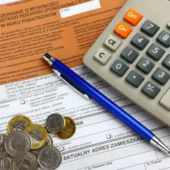 PIT-37 instrukcja: formularz podatkowy, kalkulator, długopis i monety.