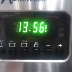 Cyfrowy wyświetlacz piekarnika Mastercook pokazuje godzinę 13:56. Ikony sugerują funkcje timera, gotowania, stopu i automatycznego trybu.