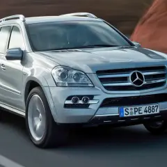 Srebrny Mercedes-Benz GL Class pędzi po drodze, za nim rozmyte krajobrazy.