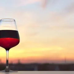 Calice di vino rosso al tramonto, con la sua acidità totale che si percepisce anche visivamente.