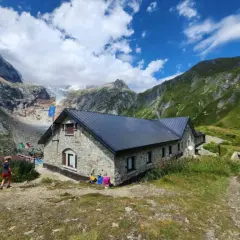 Kamienny schron na GR20 Korsyka, z lodowcem w tle i zielonymi górami.