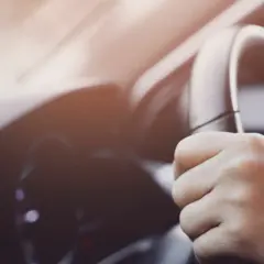 Manos sujetando el volante de un coche, con un ligero ruido al girar el volante.
