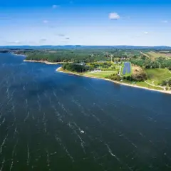 Malownicze jezioro Hańcza z piaszczystą plażą i lasem. W oddali widać farmę fotowoltaiczną, która jest jedną z atrakcji regionu.