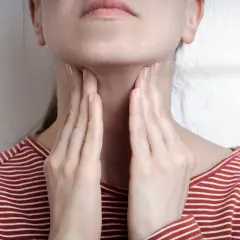 Femme touchant sa gorge, possible symptôme mononucléose. Douleur ou gonflement au cou.