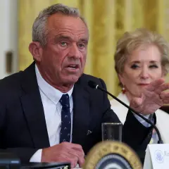 Robert F. Kennedy Jr. przemawia przy mikrofonie, obok siedzi kobieta.