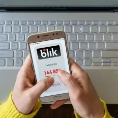 Ręce trzymają telefon z aplikacją Blik, na ekranie widoczny kod 144855. Niestety, blik nie doszedł, mimo próby skopiowania kodu.