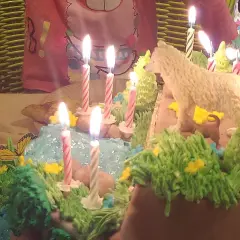 Urodzinowy tort z motywem leśnym, z figurką wilka i płonącymi świeczkami. Idealne fajne atrakcje na urodziny w domu!