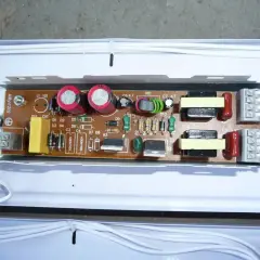 Elektroniczny statecznik z widocznymi kondensatorami, cewkami i innymi elementami na płytce drukowanej.