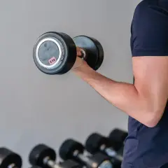Mężczyzna ćwiczy biceps z hantlem 8 kg, realizując swój plan treningowy siłownia 3-dniowy.