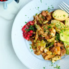 En tallrik med stuvad vitkål, köttfärs, kokt potatis, gurkband och rårörda lingon. Ett härligt kålmaja recept för en smakrik middag.
