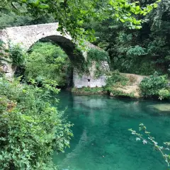 Un pont de pierre enjambe les eaux turquoise des gorges de la Siagne, entouré d'une végétation luxuriante.