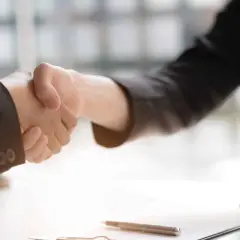 Poignée de main entre deux avocats, symbolisant un accord ou un **départage prudhomme**. Un maillet de juge est visible sur la table.