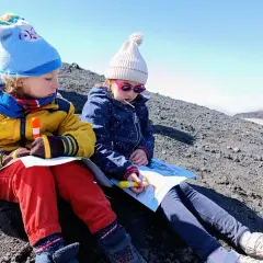Bambini vestiti a strati, con cappelli e giacche, imparano come vestirsi per andare sull'Etna.
