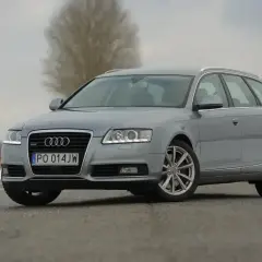 Szary Audi A6 C6 kombi na drodze. Zbliżenie na przód auta, widoczne światła, grill i tablica rejestracyjna. Wymiary tego modelu są idealne dla rodziny.