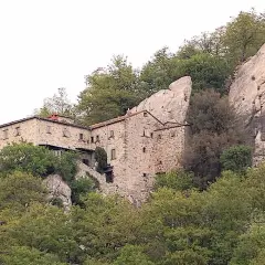 Antica pieve in pietra a Pieve Santo Stefano, incastonata tra rocce e alberi secolari, testimone di storia.