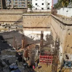 Budowa głębokiego wykopu z widoczną ścianą szczelinową, zbrojeniami i pracującymi ludźmi.