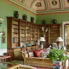 A cozy library with floor-to-ceiling bookshelves, a fireplace, and plush seating, embodying a classic countryside style.
