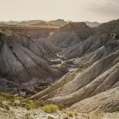 Paisaje erosionado en el desierto de Tabernas que ver. Barrancos y montañas de tierra arcillosa bajo un cielo claro.