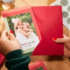 Préparation de textes de noël familial : une carte avec deux enfants souriants et des enveloppes rouges.