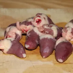 Surowe serca drobiowe na desce, gotowe do przygotowania. Dowiedz się, jak oczyścić serca drobiowe, by były idealne do gotowania.