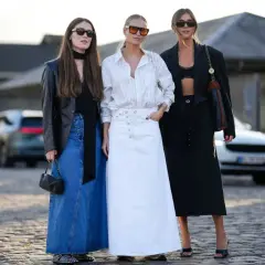 Trzy kobiety prezentują, jakie spódnice są teraz modne: dżinsowa maxi, biała maxi i czarna maxi.