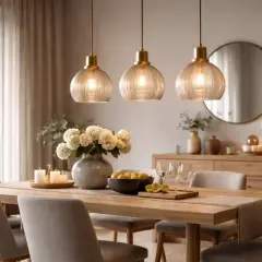 Eleganckie lampy nad stół aranżacje tworzą przytulną atmosferę. Trzy szklane lampy wiszące nad drewnianym stołem z bukietem kwiatów i cytrynami.