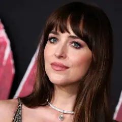 Dakota Johnson con un flequillo abierto y ojos azules intensos, luciendo un collar de diamantes.