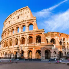 Le Colisée de Rome en novembre, sous un ciel bleu éclatant. Des visiteurs profitent de la douceur de l'automne.