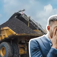 Zrezygnowany mężczyzna w garniturze na tle kopalni węgla. Czyżby kurs bogdanka okazał się zbyt trudny?