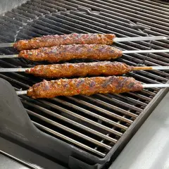 Vier saftige Adana Kebap Spieße brutzeln auf dem Grill. Das perfekte Adana Kebap Rezept für den Sommer.