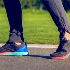 Biegacz stawia stopę, obserwując supinację. Kolorowe buty sportowe na bieżni.