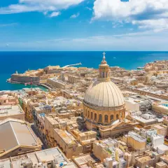 Malta w marcu: słoneczna pogoda nad Vallettą, z widokiem na morze, kopułę katedry i zabytkowe budynki.