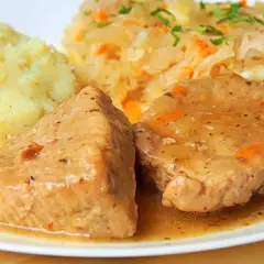 Soczysta pieczeń z szynki w sosie własnym, podana z purée ziemniaczanym i surówką z kiszonej kapusty. Pyszny, domowy obiad.