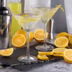 Dwa kieliszki z martini, cytryny i shaker. Idealne na orzeźwiający drink.