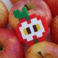 Un simpatico mele di perline, un'idea creativa per cose da fare con le perline, circondato da mele vere.