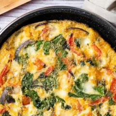 Pyszny omlet z cukinią, szpinakiem i pomidorami, zapieczony w patelni. Idealny na śniadanie lub lekki obiad.