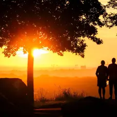 Ein Paar steht im Sonnenuntergang. Sie hat einen neuen Partner nach dem Tod ihres Ehemannes gefunden und blickt hoffnungsvoll in die Zukunft.