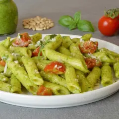 Penne al pesto di rucola con pomodorini freschi e pinoli tostati. Un piatto colorato e saporito.