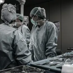 Chirurghi in sala operatoria discutono. Quanto guadagna un medico legale al mese? La risposta è complessa, ma il loro lavoro è fondamentale.