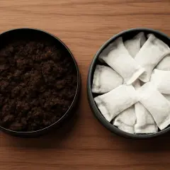 Två dosor på ett träbord: en med lössnus, den andra med portionssnus. Ett alternativ till cigaretter.