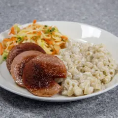 En tallrik med stekt korv, krämiga makaroner och en fräsch sallad. En klassisk och mättande måltid.